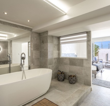 fr Chambre Mauï : un Lit double 160 cm, TV, penderie et salle de bain attenante ouverte sur la chambre avec douche à l’italienne et baignoire îlot, meuble vasque et toilettes séparées. Petit salon extérieur vue mer.