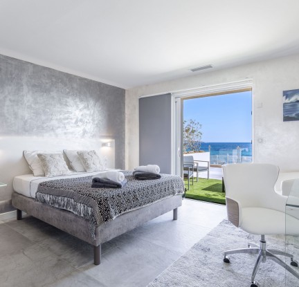 La chambre Tahaa : Lit double 160 cm, TV, penderie et salle de bain avec douche à l’italienne et baignoire balnéo, meuble vasque et toilettes séparées. Petit salon extérieur vue mer.